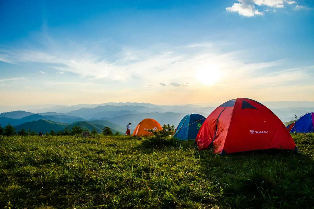Campamento con tiendas de colores en una loma con vista a las montañas