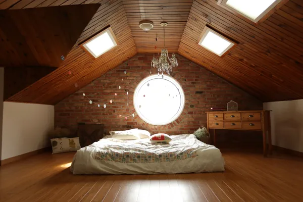 Dormitorio en altillo con luz natural y cama ordenada