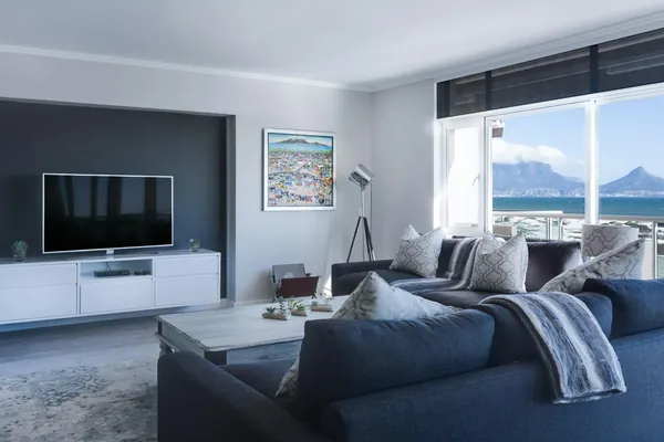 Salón bañado de luz natural con ventanal y sofá azul marino