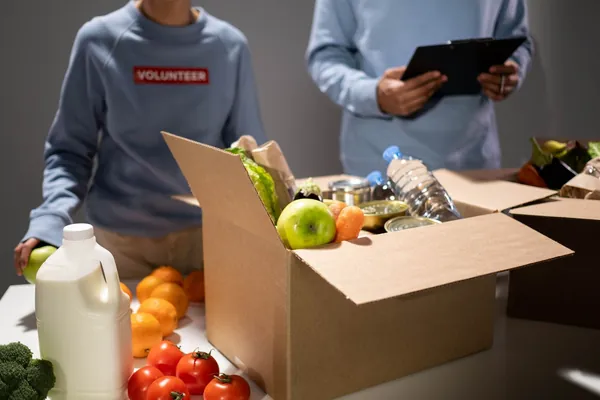 Voluntarios empacando cajas con alimentos frescos y enlatados